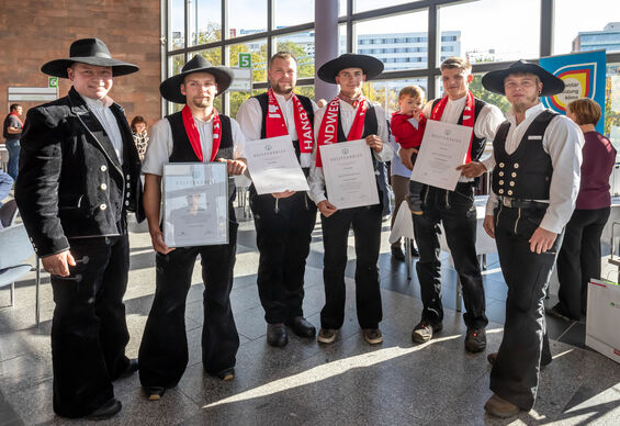 Eine Gruppe Zimmerermeister in Tracht lacht in die Kamera. 