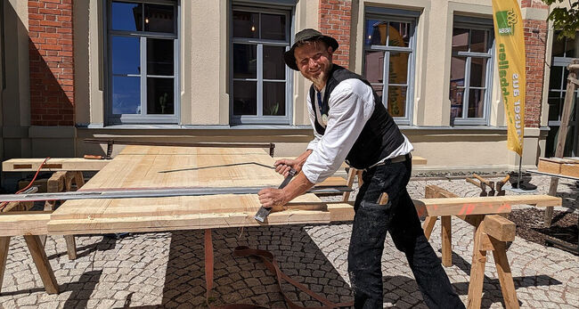 Zimmermann bearbeitet Holz