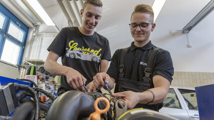 Zwei lachende Gesellen beim Motormanagement.