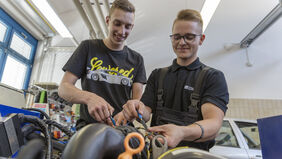 Zwei lachende Gesellen beim Motormanagement.