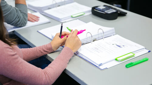 Auszubildende sitzt in der Berufsschule vor ihren Arbeitsmaterialien.