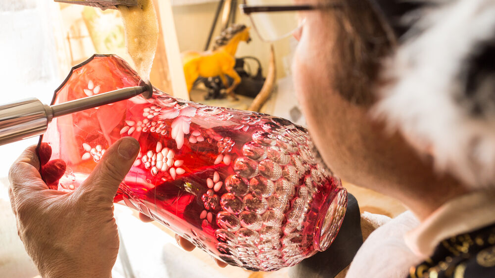 Glassschleifer bei der Bearbeitung einer roten Glasvase.