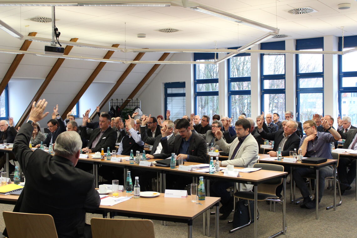 Gruppe von Menschen die zur Abstimmung die Hand heben