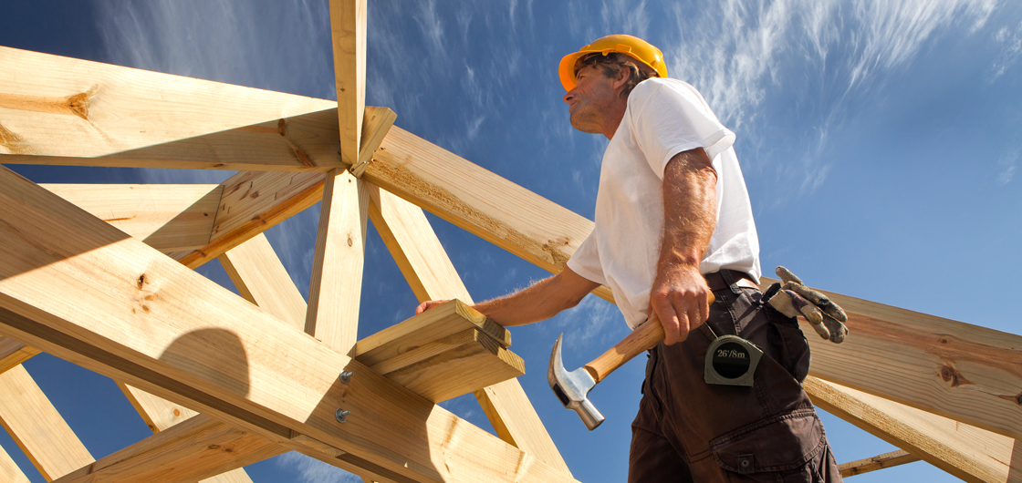 Zimmerer-Meister auf dem Dach beim befestigen von Holzbalken 