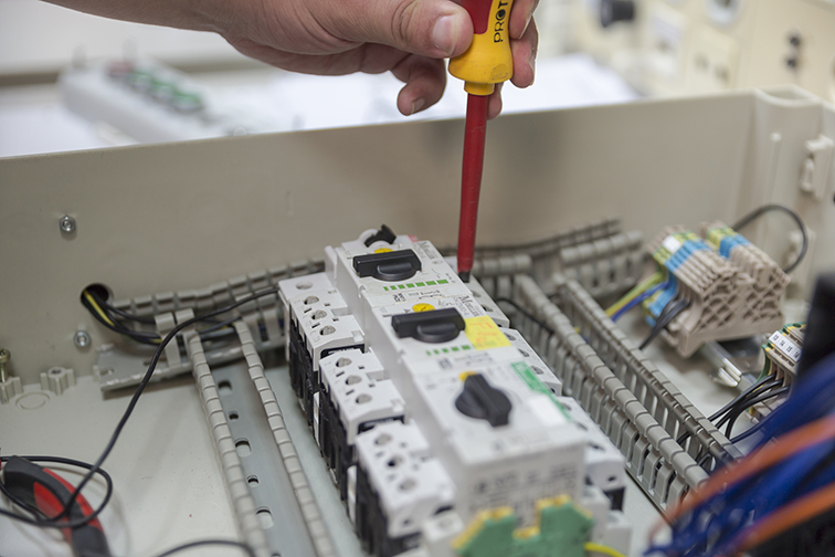 Das Bild zeigt die Hand eines Auszubildenden mit einem Schraubenzieher bei der Verdrahtung eines Schaltschranks. In den Bildungs- und Technologiezentren der Handwerkskammer Chemnitz werden von den Grundlagen in der Ausbildung bis zum Meister sämtliche Ausbildungsinhalte vermittelt und diese im Zuge von Fortbildungslehrgängen stetig auf dem Stand der aktuellen Technik, von Normen und Gesetzen gehalten.