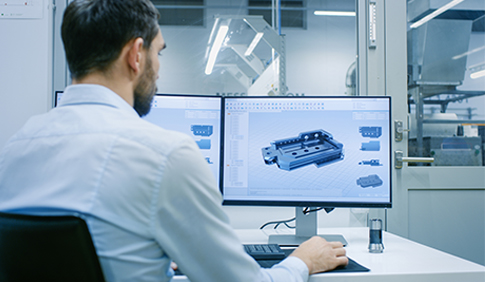 Ein Mitarbeiter sitzt an einem Schreibtisch und arbeitet mit einem AutoCAD Programm.