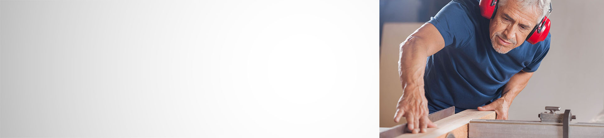 Älterer Mann mit Gehörschutz am Kreissäge
