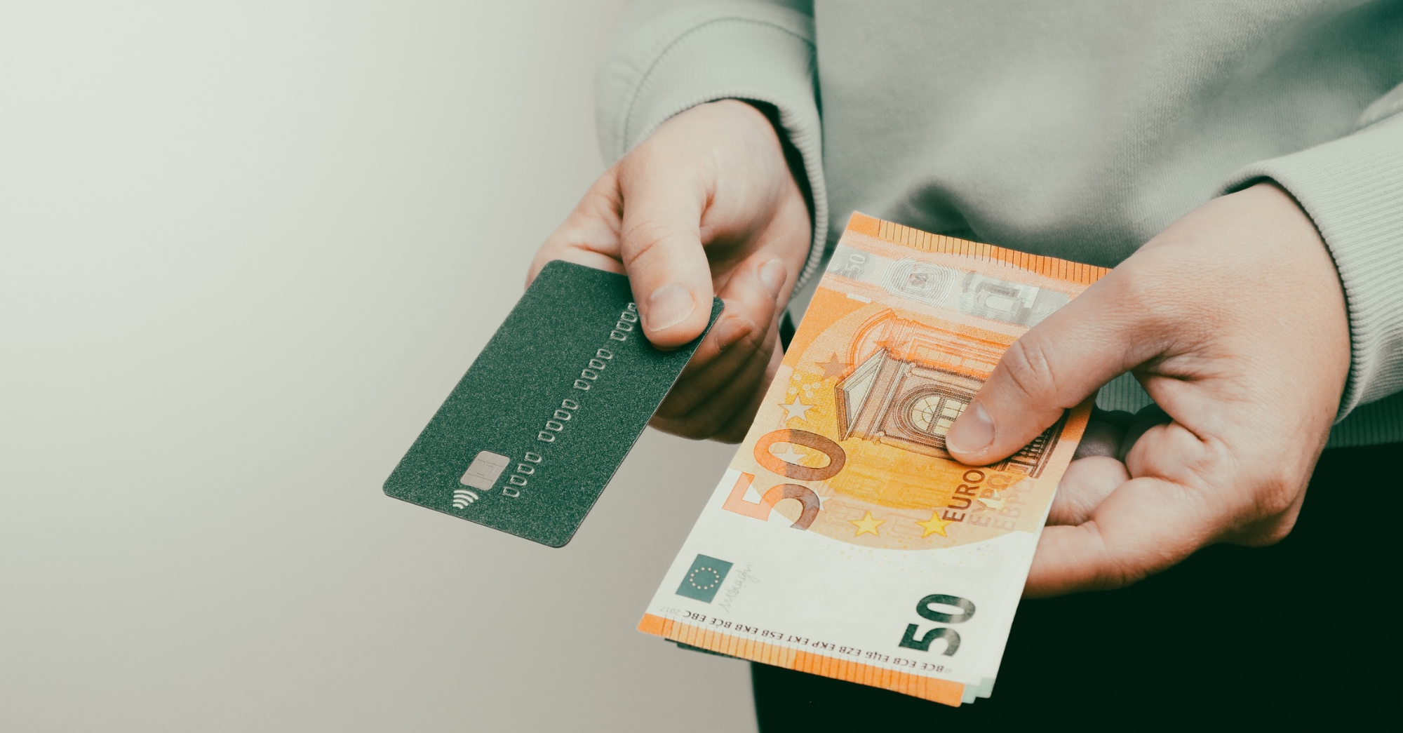 Männerhände halten mehrere Geldscheine und eine Kreditkarte.