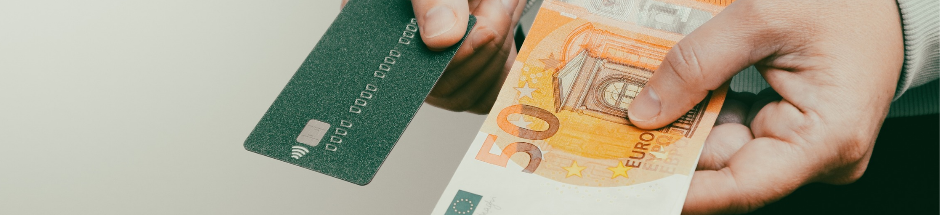 Männerhände halten mehrere Geldscheine und eine Kreditkarte.