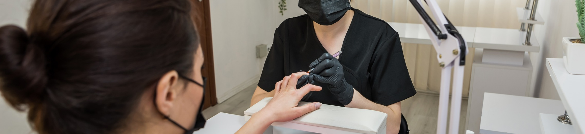 Kosmetikerin behandelt Kundin an den Fingern.